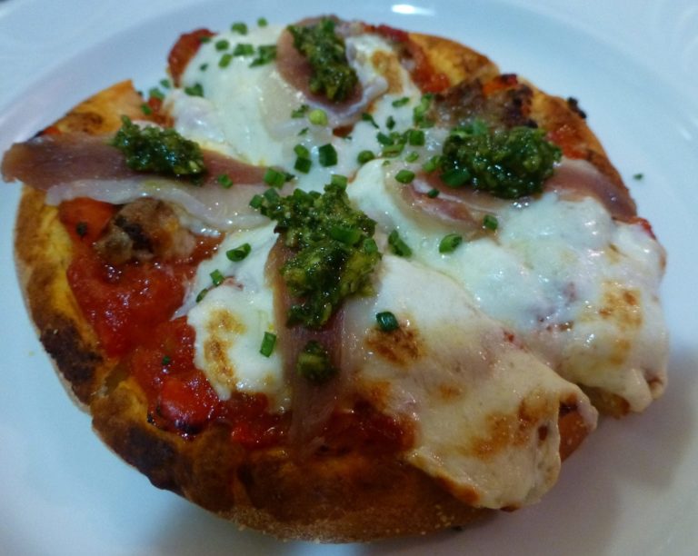 small pizza topped with tomatoes, cheese and pesto