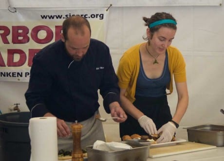 Two chef's plating food at a festival table