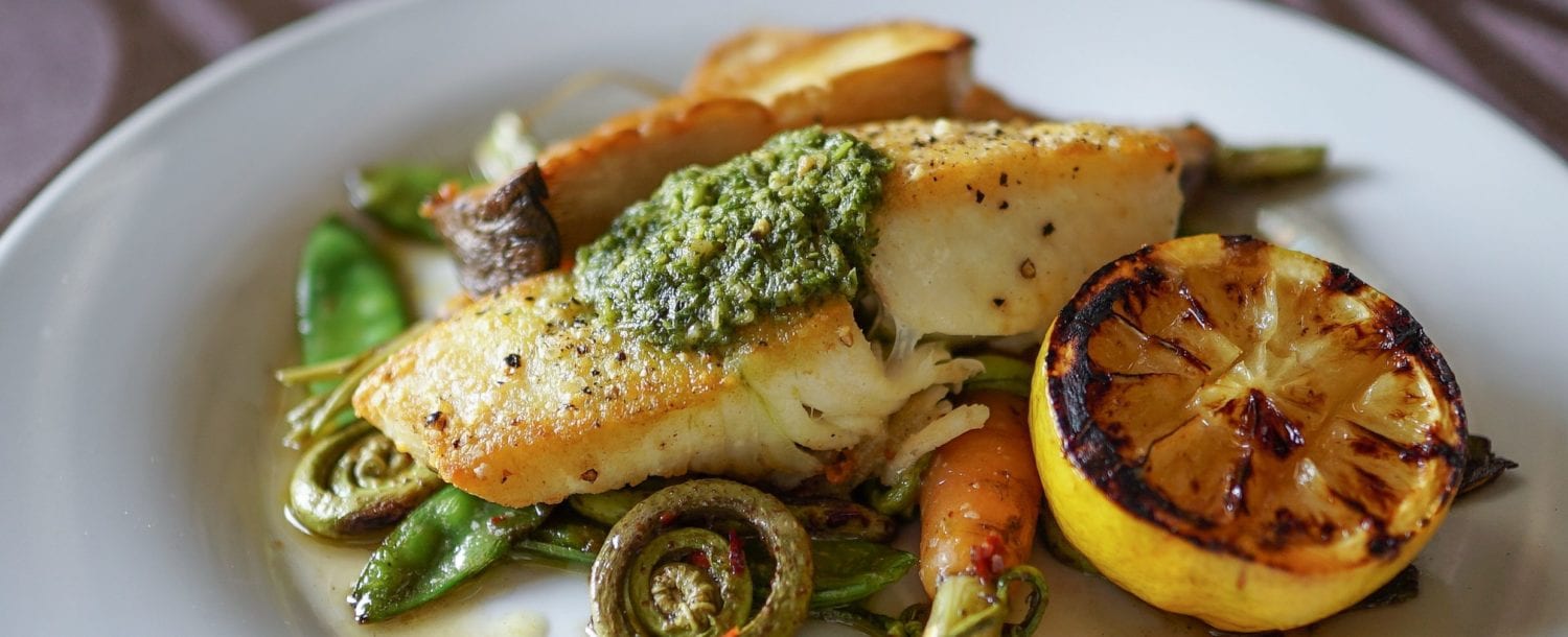 white fish with pesto and roasted fern fronts, carrots, and peas