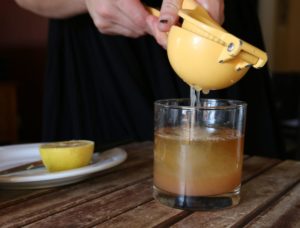 squeezing lemon juice into a cockatil