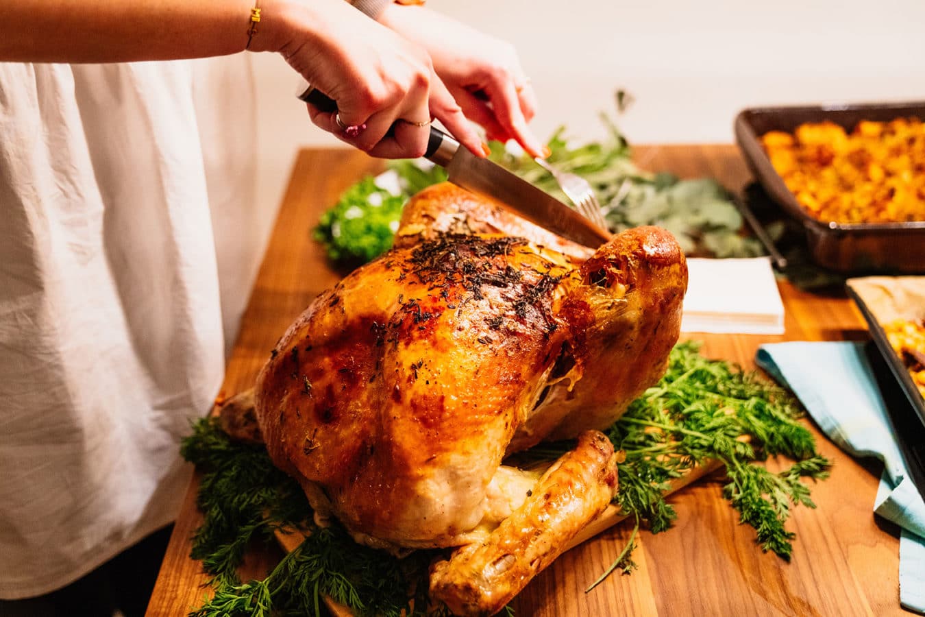 person carving a turkey on a wooden board