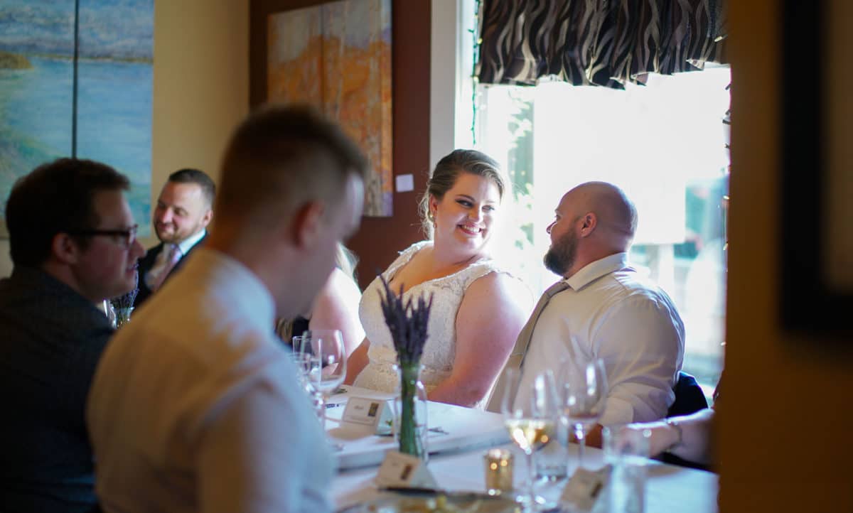 Bride and groom at a dining table in a restaurant surrounded by friends