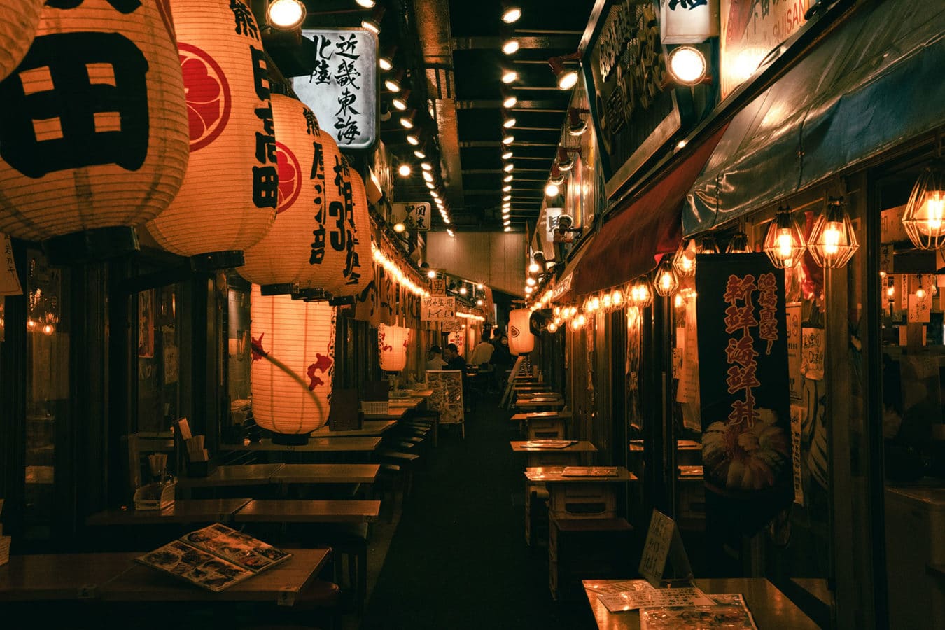 Tokyo street at night with lanterns and restaurant tables set with menus