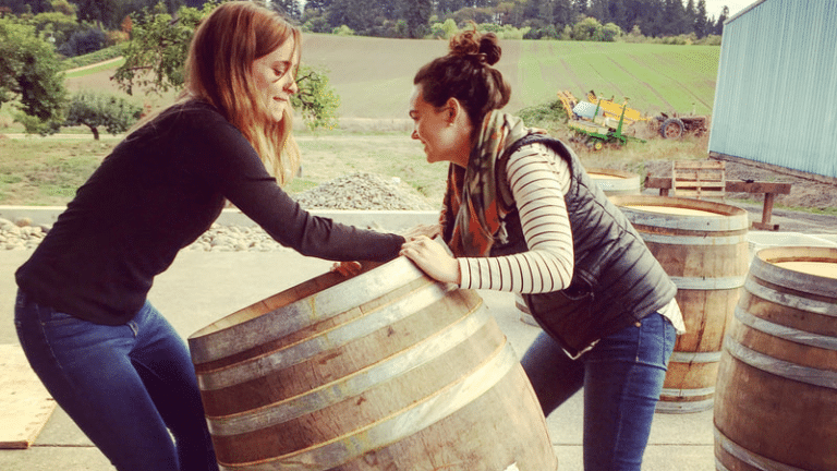 Two women moving a large wine barrel